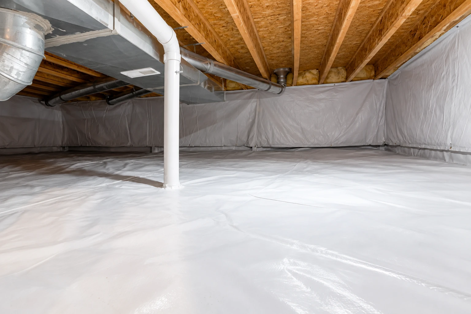 A crawl space has white vapor-barrier sheeting across the floor and walls, with ducts and a support post overhead.